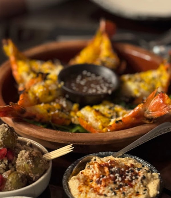 Grilled jumbo prawns with butter-corn topping and dipping sauce, served with hummus and olives.