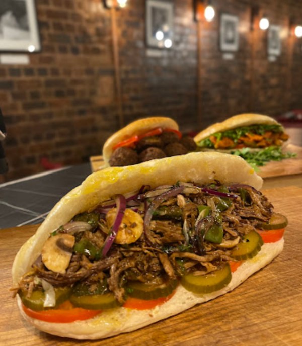 Soofi Restaurant's sandwich filled with shredded meat, grilled vegetables, and pickles.